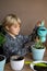 Boy planting and watering a flower in a pot.