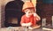 Boy play as builder or repairer, work with tools. Kid boy in orange hard hat or helmet, study room background. Child