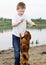 Boy play on the lake bank with dog