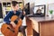 Boy playing acoustic guitar and watching online course on laptop while practicing at home. Online training, online classes