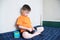 Boy playing car game,boy playing with toys sitting on bed indoor,kid holding two toy cars alone