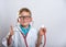 Boy playing doctor with a stethoscope. Kid in glasses isolated over white. Thumb up.