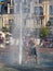 boy is playing in the fountain. Wet child in the fountain. Splashes of water on a person. Wet clothes on the guy.
