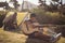 Boy playing guitar while father setting up a tent in park