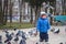 Boy playing with pigeons doves birds in city park