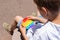 Boy playing with rainbow anti stress pop it toy, outdoors