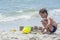 Boy playing with sand on the beach, building towers,