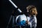 Boy playing to be an astronaut with space helmet and metal suit. Portrait of funny kid with astronaut helmet on black.