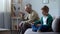 Boy playing video game on tablet, paying no attention at lonely grandfather