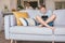 Boy plays with electronic device. His mother prepared something in the blurred background kitchen