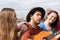 A boy plays the guitar together with two girls in a city park