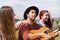 A boy plays the guitar together with two girls in a city park