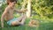 Boy plays with Orange Scottish Fold kitten with a branch, on grass in garden