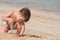 The boy plays sand on seacoast