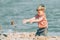 A boy plays on the sea and throws sand on the beach