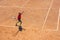 The boy plays tennis on the orange dirt court. Court hard