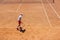 The boy plays tennis on the orange dirt court. Court hard