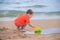 A boy plays a typewriter on the beach. Children`s games. Beach in the summer. Small child