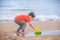 A boy plays a typewriter on the beach. Children`s games. Beach in the summer. Small child