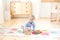 The boy plays with a wooden typewriter. Educational wooden toys for the child. Portrait of a boy sitting on the floor in the child