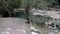 Boy with ponytail and oversize t-shirt crosses a river on foot