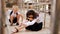 A boy on the porch of the school mocks a classmate in a school uniform crying sitting on the floor. Bullying at school.