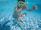 A boy poses for the camera under water in a swimming pool on holiday.