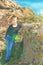 A boy poses for a photo shoot, leaning on a large rock on the rocks during a hike