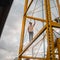 Boy posing on top of a yellow structure and tower. Boy on a dangerous adventure on top of a tower.