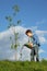 Boy pours on seedling of tree by water