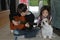 Boy practicing playing guitar, his sister listens to the music