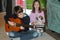 Boy practicing playing guitar, his sister sings