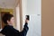 A boy presses buttons on the control panel to disarm the burglar alarm system