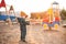 A boy in a protective mask plays in the playground and spills sand from his hands during the pandemic of coronavirus and Covid -