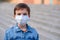 Boy in protective mask stays in schoolyard