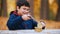 A boy pulls a knife out of the table and eats canned stewed meat