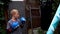 A boy punches a punching bag in blue gloves in the yard