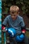 A boy punches a punching bag in blue gloves in the yard