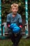 A boy punches a punching bag in blue gloves in the yard