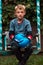 A boy punches a punching bag in blue gloves in the yard