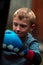 A boy punches a punching bag in blue gloves in the yard