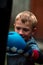 A boy punches a punching bag in blue gloves in the yard