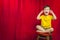 Boy Puts Fingers In Ears on Stool in Front of Theater Curtain