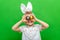 Boy in rabbit bunny ears on head on green studio background. Cheerful crazy smiling happy child. Easter blue color of