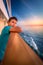 Boy at the railing of a cruise ship at sunset.
