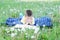 Boy reading book lying on stomach outdoor among dandelion in park, smiling cute child, children education and development. Back to