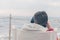 A boy in a red jacket and headphones looks at the sea waves in stormy weather