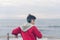 A boy in a red jacket and headphones looks at the sea waves in stormy weather