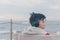 A boy in a red jacket and headphones looks at the sea waves in stormy weather