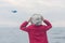 A boy in a red jacket looks at the sea waves in stormy rainy weather. Landing plane above sea waves in stormy rainy weather